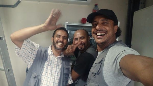 Trois techniciens de l’équipe Dorylab, souriants, devant un tableau électrique