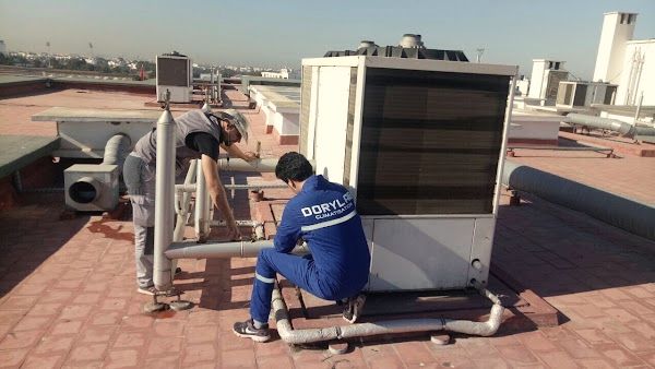 Deux techniciens, dont un en tenue Dorylab, travaillant sur une grande unité de climatisation installée en toiture