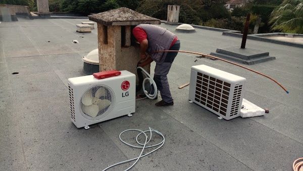 Technicien sur un toit-terrasse, à côté d’une unité extérieure LG et d’une unité intérieure posées au sol