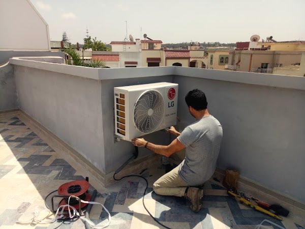 Technicien fixant une unité extérieure LG au mur d’une terrasse carrelée